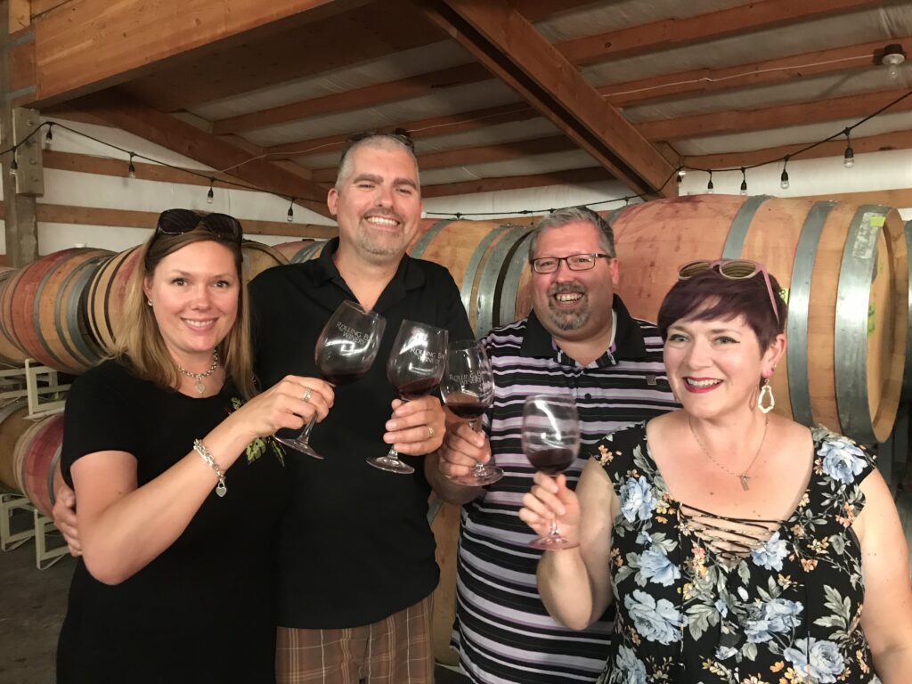 Two couples drinking wine in a barrel room