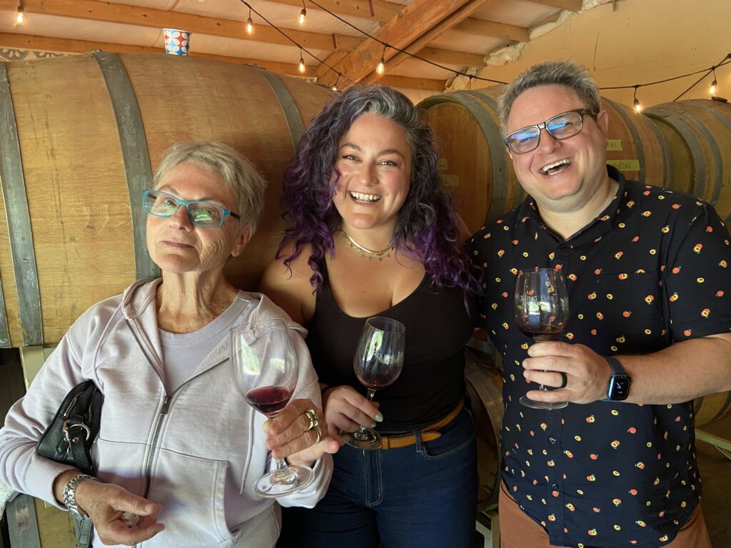 image of three wine tasters standing in front of barrels